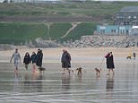 Beach goers in Cornwall wrap up as showers spreads across much of the country from the west